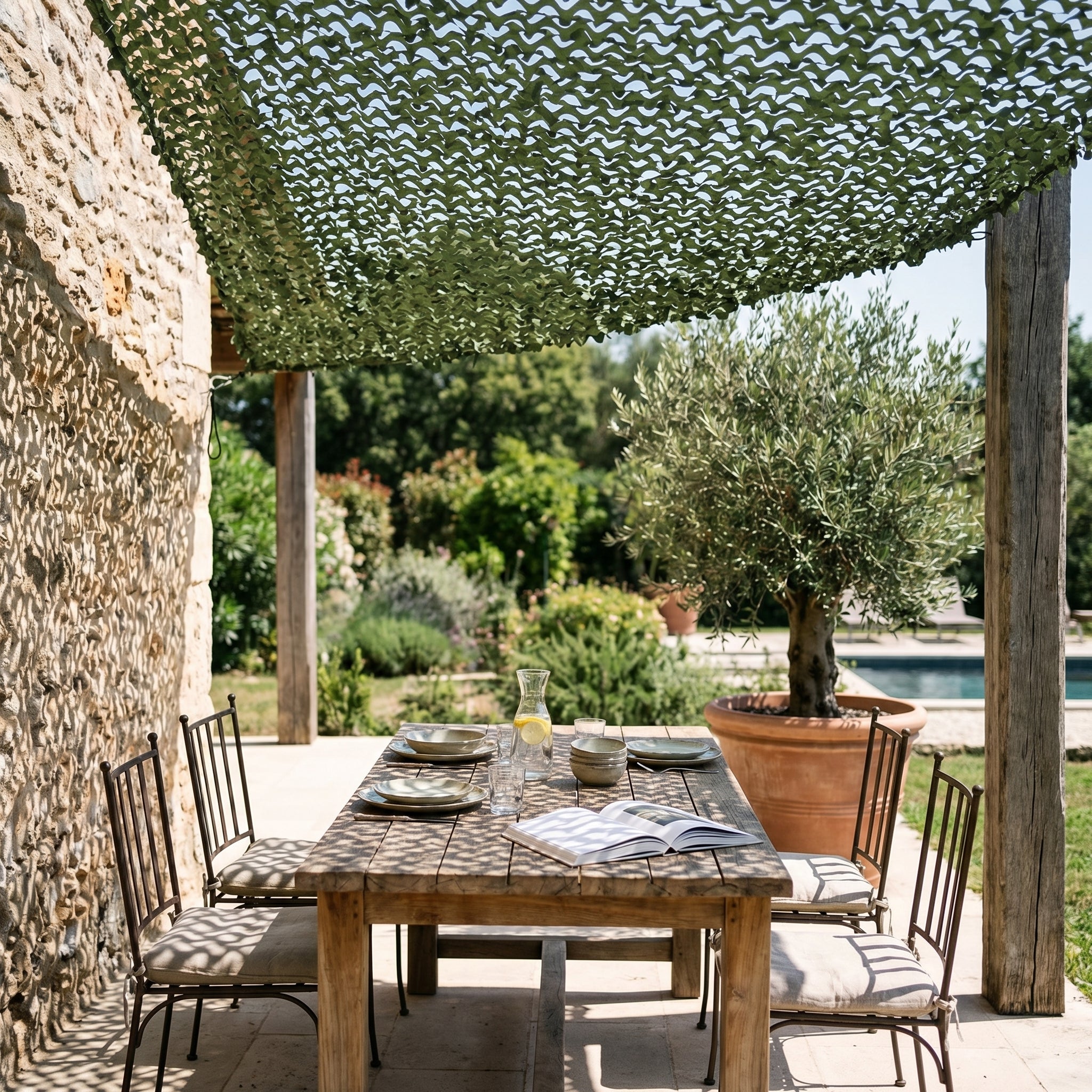 TheFrenchNets olive triangle shade net anchored at a leafy garden corner.
