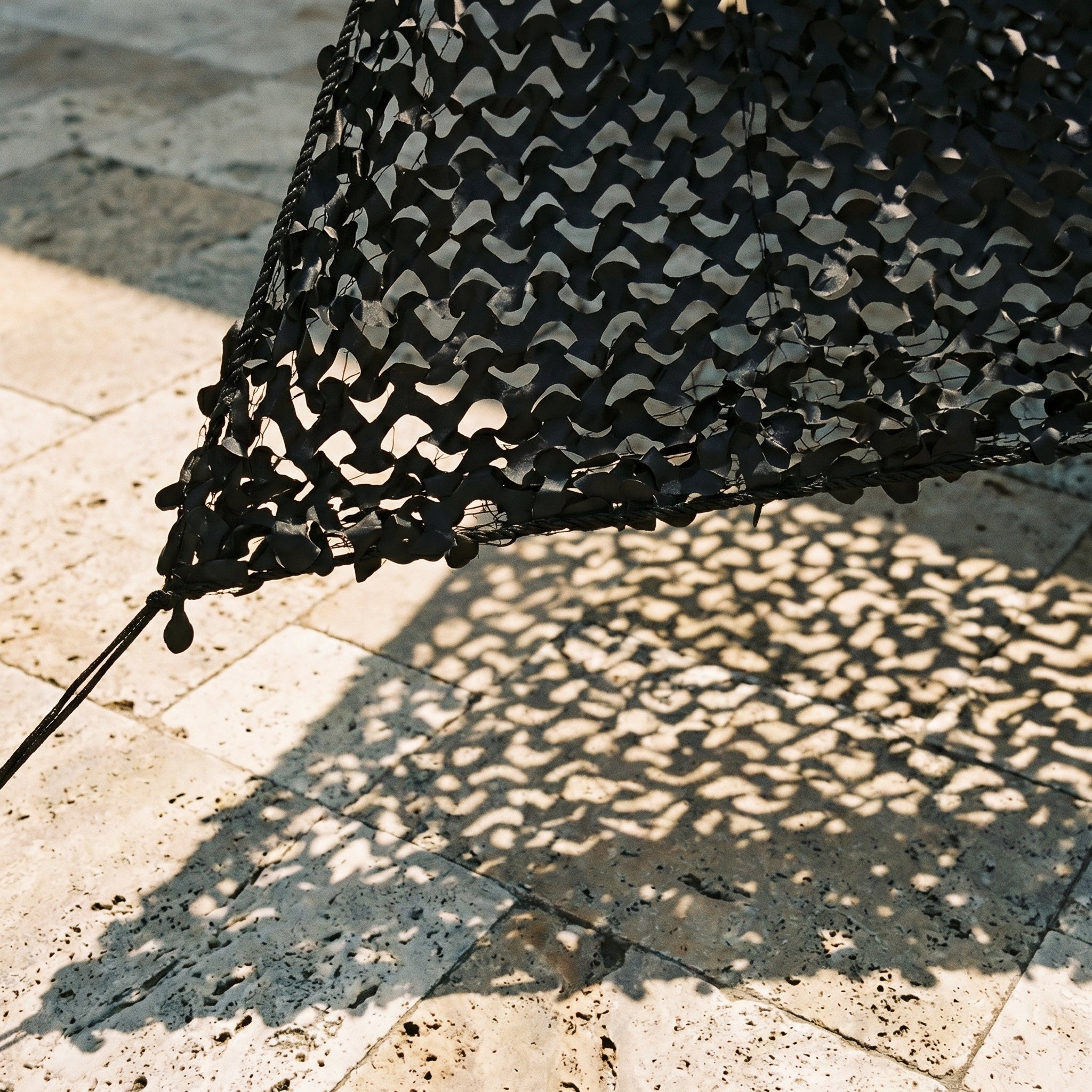 TheFrenchNets jet black triangle shade net anchored above a minimal rooftop.