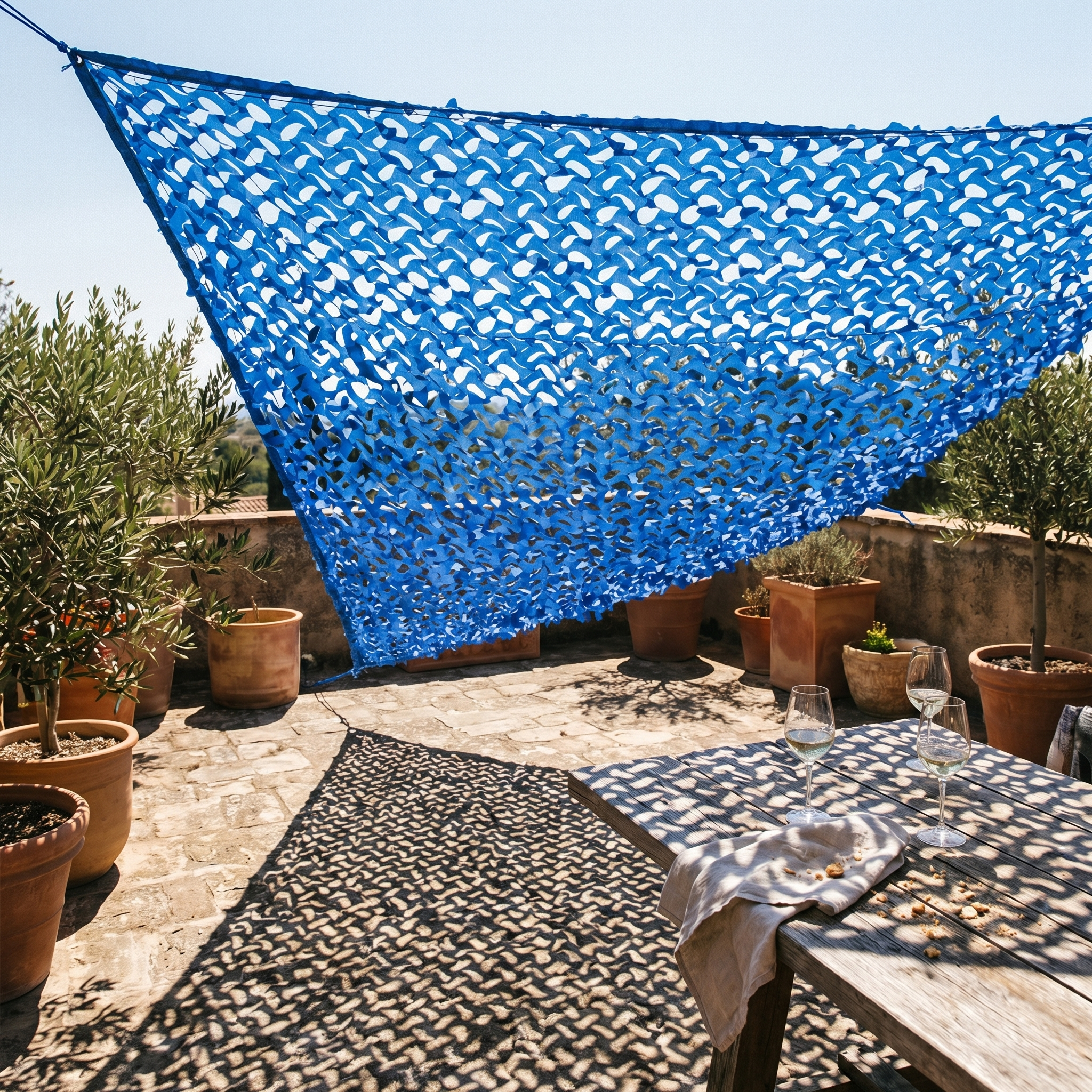 TheFrenchNets blue triangle shade net anchored across a lakeside terrace gap.