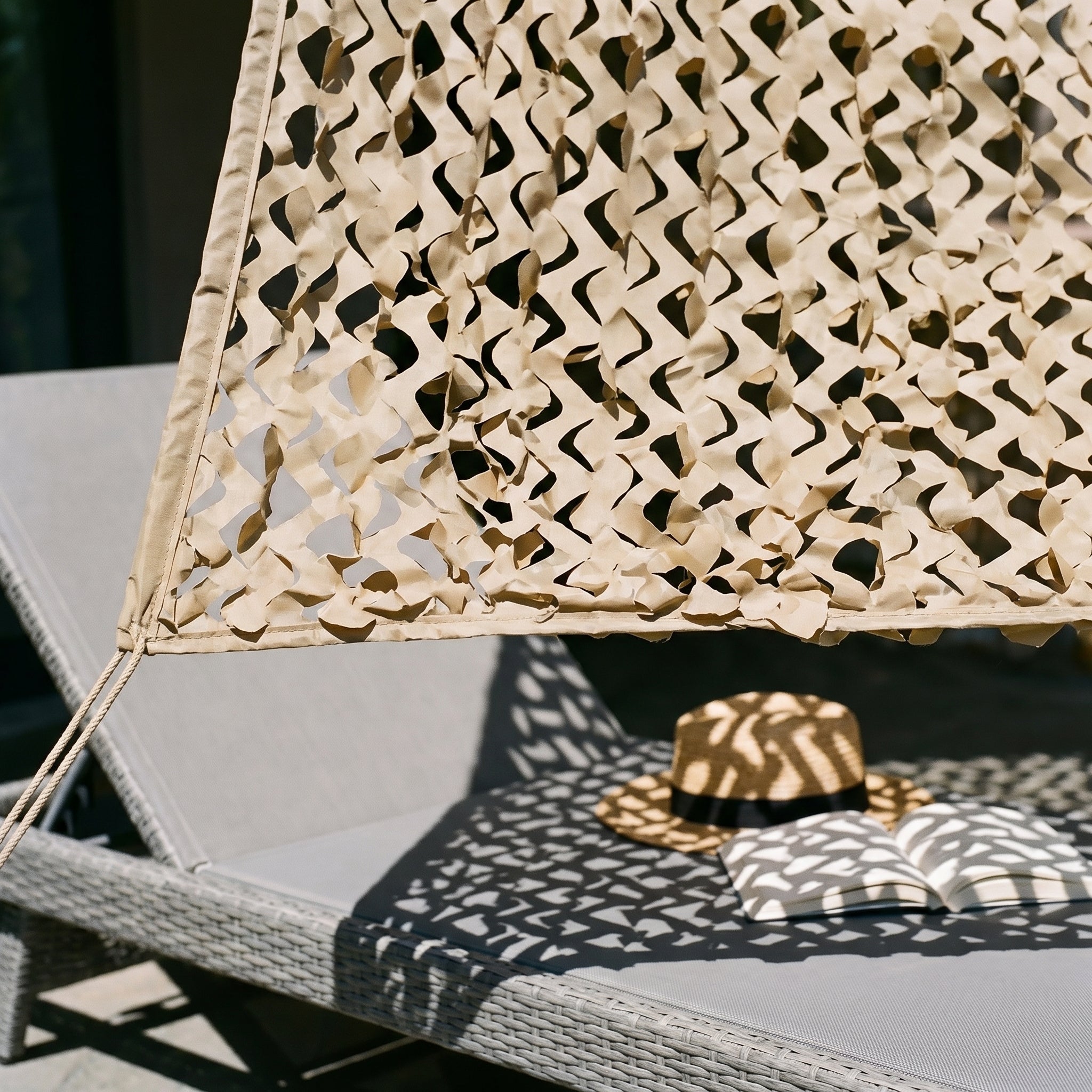 TheFrenchNets sand triangle shade net anchored to a stone courtyard wall.